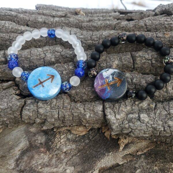 Two bracelets with Sagittarius Zodiac sign charms, on a log.
