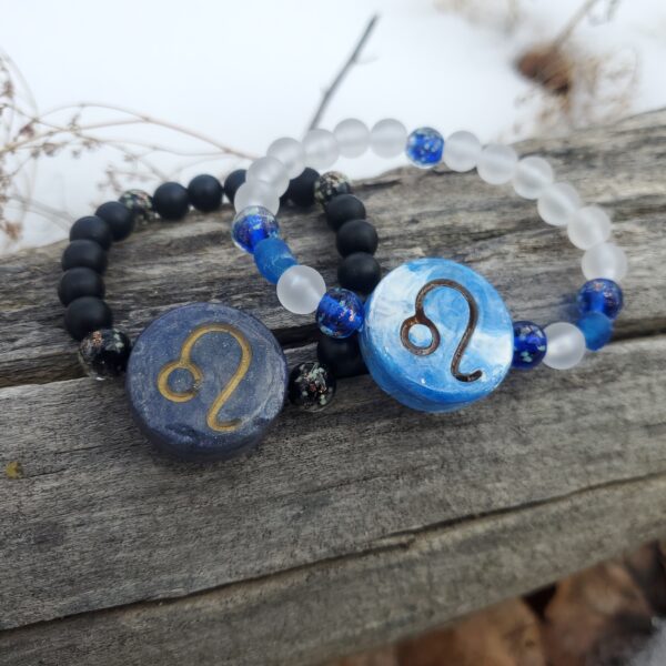 Two bracelets with Leo Zodiac sign charms, on a log.