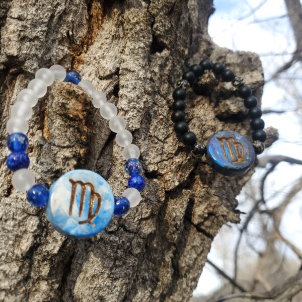 Two bracelets with Sagittarius Zodiac sign charms, hanging from a tree.